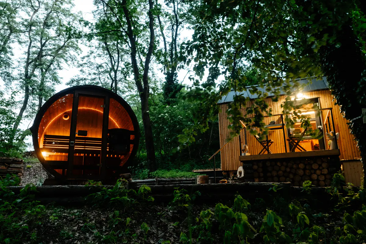 The Hrubá Skála cabin and barrel sauna at dusk