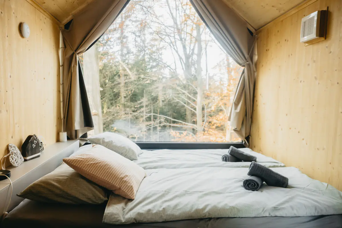 Bed by a large window looking into the forest
